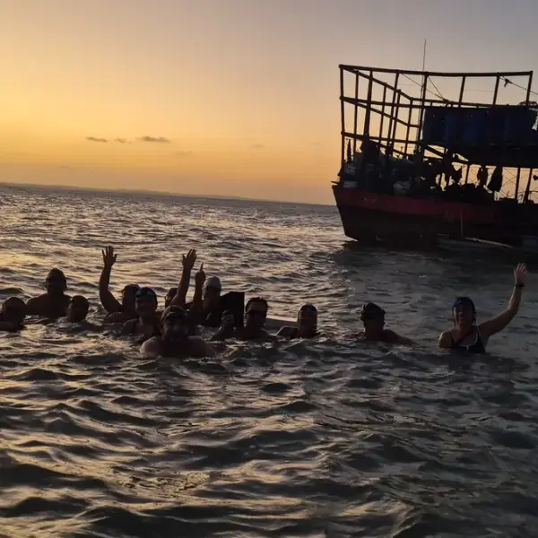 Grupo de nadadores no mar ao pôr do sol