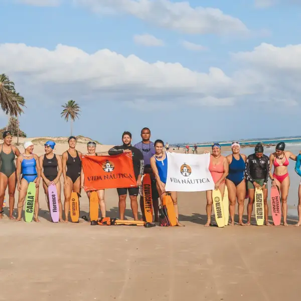 Equipe na praia, cada pessoa segurando um flutuador com o próprio nome